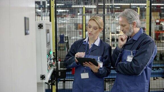 男性和女性工厂员工谈论的价值显示在机器的LCD屏幕上