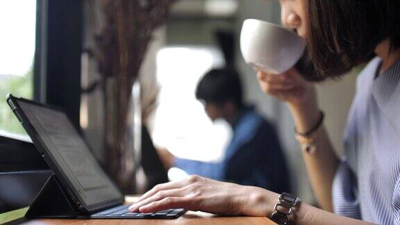在平板电脑工作的女人在咖啡馆喝咖啡慢镜头