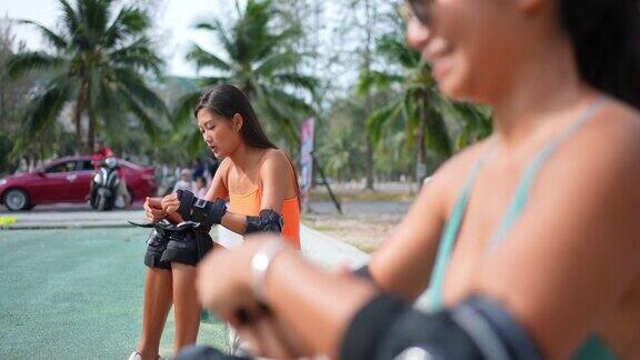 在滑板公园玩滑板前亚洲妇女和女友们穿着安全的滑板手臂护垫