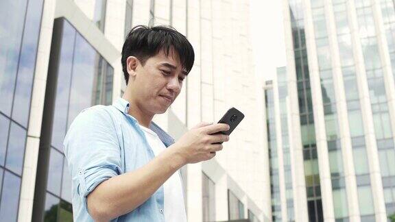 年轻的亚洲男子使用手机与现代办公大楼