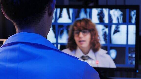 亚洲男性医生视频通话白种人医生在教育研究x光骨视频会议而在远程地点通过电脑在家里晚上工作到很晚高科技会议