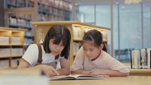 MS两个年轻女孩一起在图书馆放松