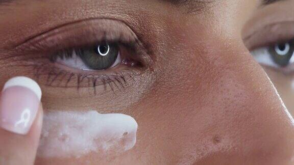 一个女人在工作室背景下涂抹润肤霜的4k视频片段