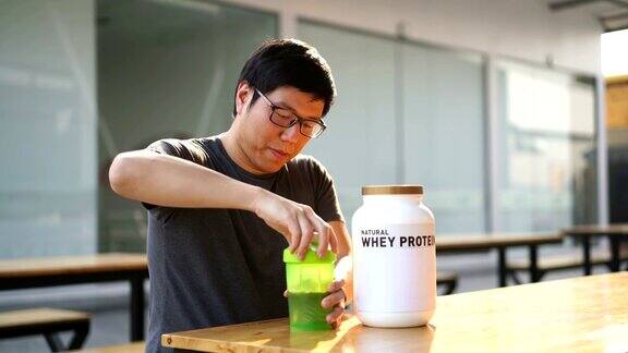 亚洲男人在健身后喝乳清蛋白饮料