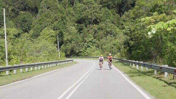 职业自行车手在乌鲁兰加乡村地区骑公路旅行与2名铁人三项运动员骑手在早上