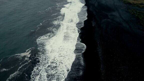 在冰岛的黑色火山海滩上海浪来海岸的Aeial视图背景上的山