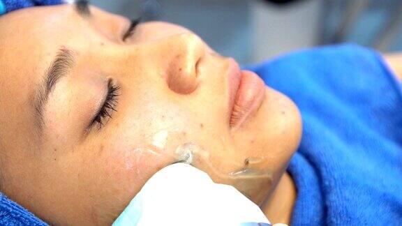 抗衰老面部护理与霜按摩在女人的脸上