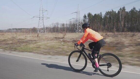 在自行车上使劲蹬的女人戴头盔的女性正在骑自行车骑公路自行车的人训练女孩骑户外铁人三项