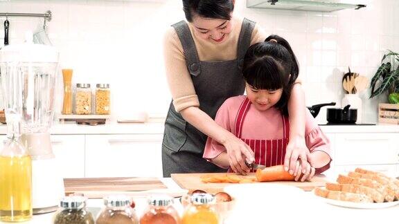 摄影车正面拍摄:日本母亲和女儿在厨房里一起切胡萝卜