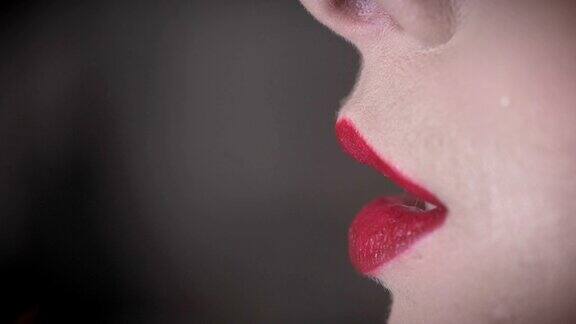 在女人的嘴唇上涂上红色唇膏特写