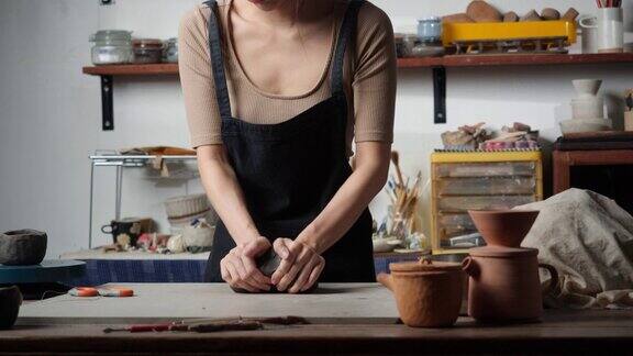 无名年轻女子在陶艺工作室用木头塑造粘土陶艺女孩把粘土压扁到盘子里教育理念、商业、艺术人才和手工创作