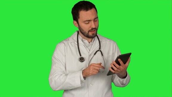 医生拿着他的平板电脑看着摄像头在医疗办公室的绿色屏幕色度键