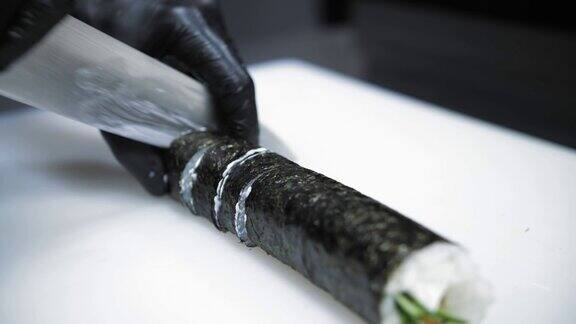 寿司日本的食物烹饪烹饪寿司师傅正在把寿司卷切成小块奶油芝士寿司黄瓜食材米饭海苔特写镜头在餐厅的厨房