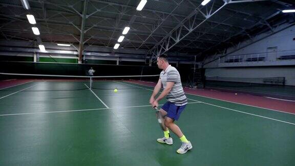身穿白色运动服的男子用球拍发球和回击弹跳的球参加训练比赛的职业运动员两个男人在室内球场打网球