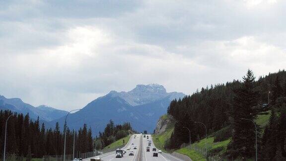车辆行驶在横跨加拿大高速公路下的阴天与森林和加拿大落基山脉的背景在阿尔伯塔加拿大