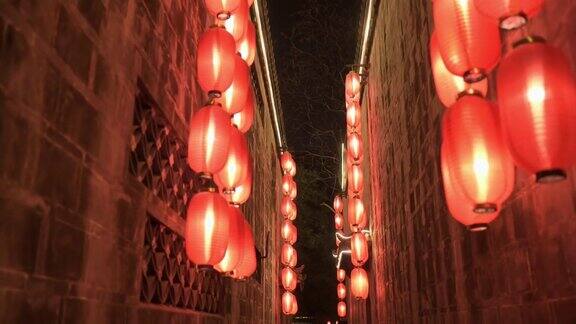 晚上在古庙狭窄走廊的石墙中间往前走点燃了红灯笼四处悬挂着照明灯传统装饰节日庆典