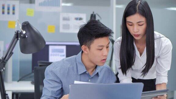 在办公室里领导亚洲商业女性与年轻男性一起使用平板电脑分析数据并在晚上工作到很晚的时候找到解决方案高科技会议年轻企业家在工作