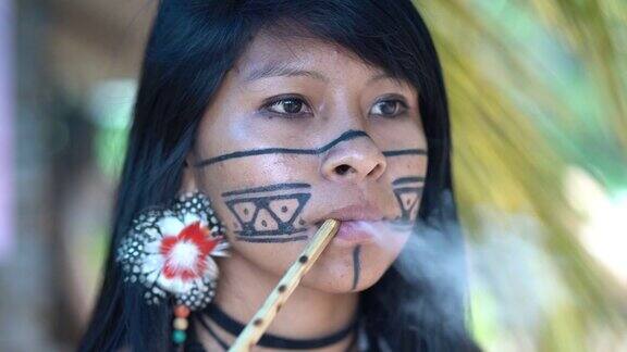 土著巴西年轻女子抽烟斗来自瓜拉尼民族