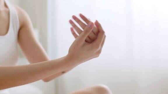 近距离年轻的亚洲妇女应用手霜和乳液护肤品的手