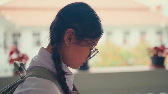 一个女学生独自走在学校走廊上表情悲伤