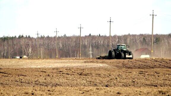 农业综合企业农民在他的土地上开始春季的农业工作时用拖拉机耙土