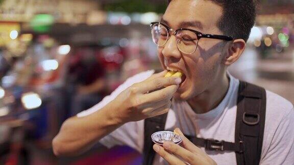 一名亚洲男子在泰国曼谷街头吃蛋挞