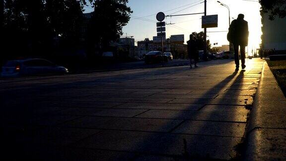 日落时城市街道上人影和汽车的剪影