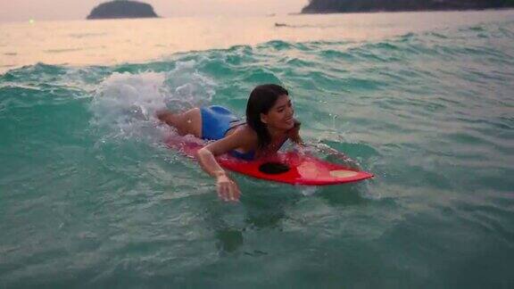 4K亚洲女人在夏日日落的海面上冲浪