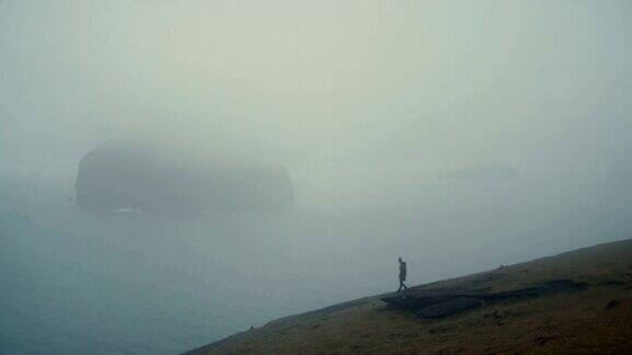 在一个雾天一名年轻女子站在海边一边欣赏着冰岛的美景一边想着什么