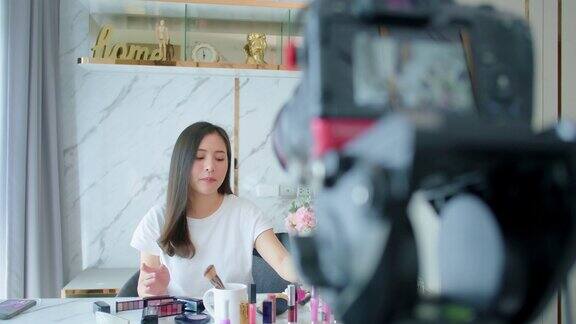 肖像年轻的亚洲女性评论化妆品产品粉丝跟踪频道录制视频化妆唇彩化妆品在家美妆博主呈现美妆