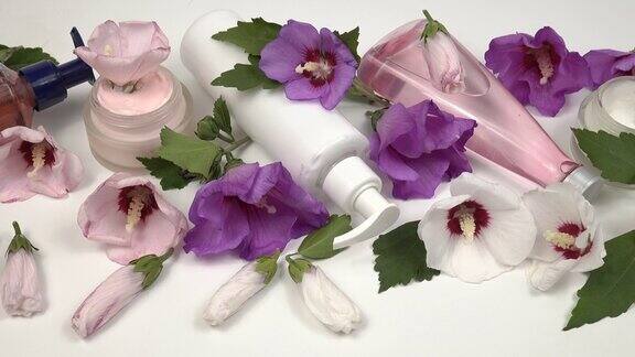 护肤产品以锦葵植物和锦葵花为基础放在白色的桌子上
