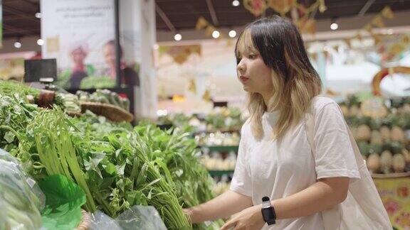 一位女士在超市挑选蔬菜