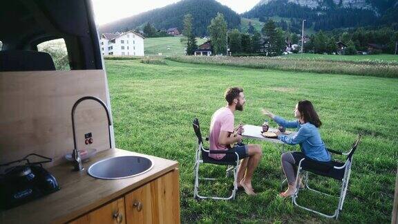 女人和男人坐在露营车附近的桌子旁