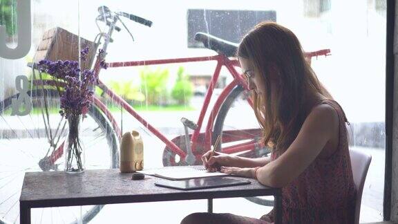 年轻的商业女孩在咖啡馆用笔记本电脑工作