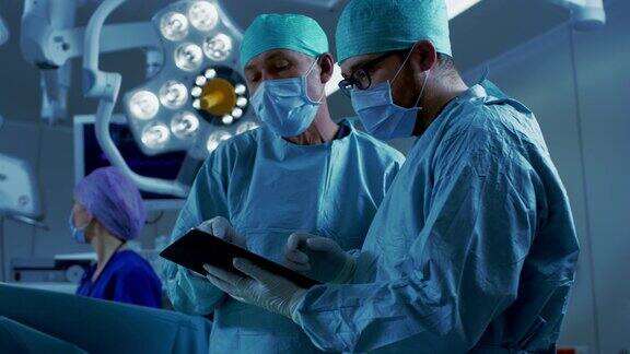 专业的外科医生和助理站在现代医院手术室里使用数字平板电脑说话