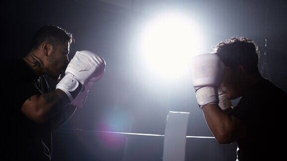 拳击场内的两名拳手戴着拳击手套在戏剧性的灯光下凝视着对方