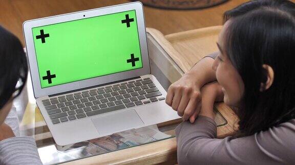 夫妇使用绿色屏幕笔记本电脑的后视图