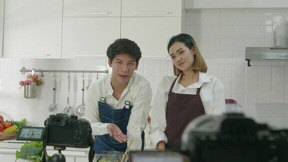 年轻的亚洲夫妇在厨房里直播博客