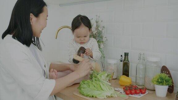 年轻女子做饭在家里的厨房和可爱的小女儿说话