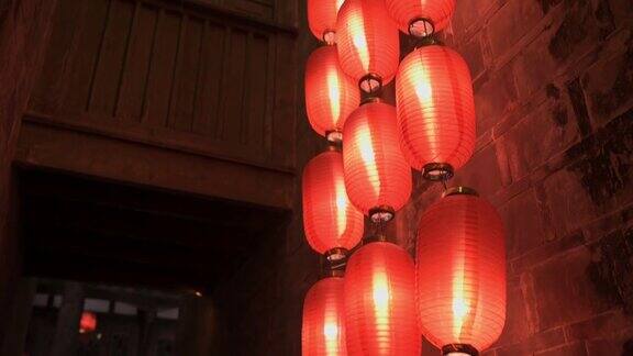 从下到上拍摄的中国寺庙的石墙和阳台在晚上点燃的红灯笼悬挂在屋顶的柱子上照亮灯光传统装饰东方节日庆典