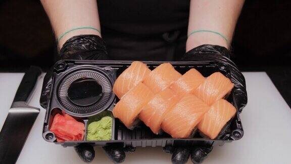戴着黑色手套的厨师展示完成的寿司