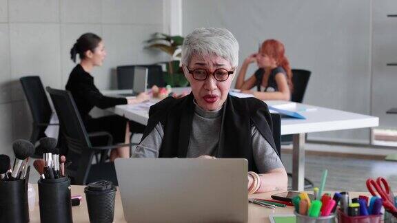 高级女化妆师在家庭办公室的笔记本电脑上学习在线课程