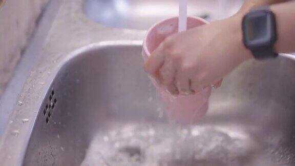 女人的手清洁硅胶旅行粉色马克杯在水槽