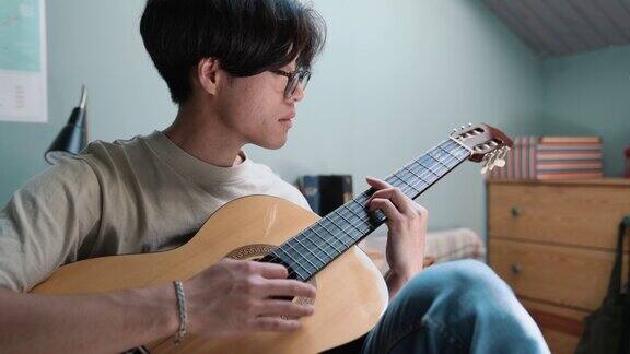 高兴的亚洲人在床上弹吉他