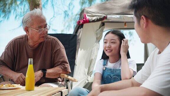 快乐的亚洲家庭与年长的祖父野餐和露营在热带海滩夏天的活动放松和户外活动的生活方式家庭概念