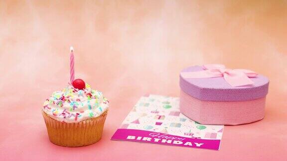 生日派对杯蛋糕与白色奶油和蜡烛出现在桌子上与贺卡和生日礼物-停止运动