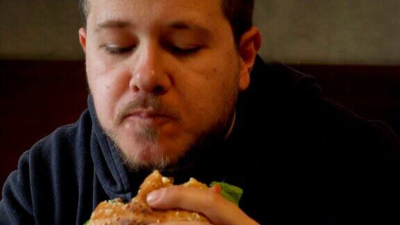 男人把一个大汉堡装上字节男人吃汉堡的肖像