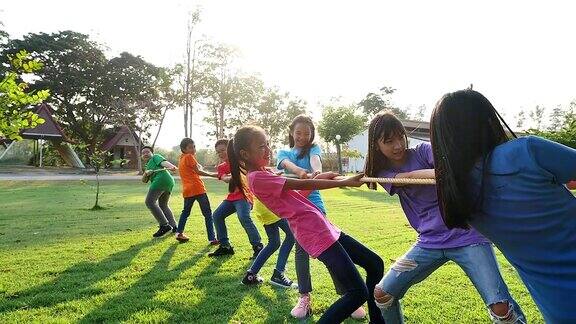 一群学龄前儿童在公园里玩拔河游戏户外游戏童年友谊领导儿童节