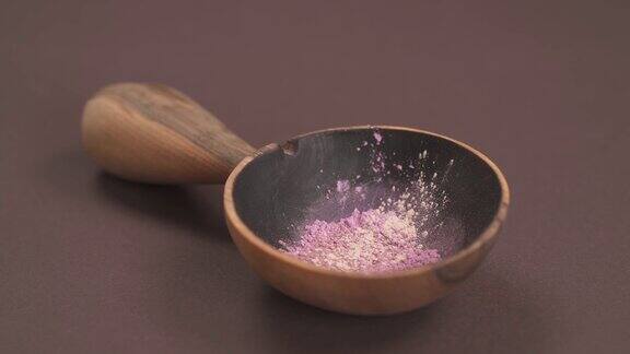 特写的紫药粉放入木碗中用手将白花粉加入碗中天然化妆品的准备环保产品