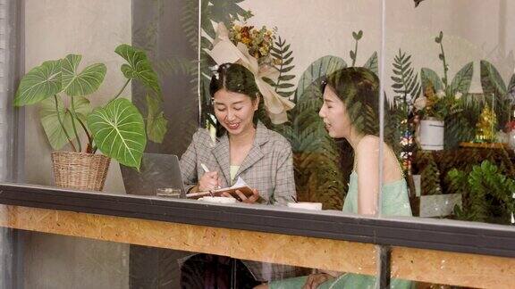 两个亚洲女人是好朋友在度假的时候出去找朋友在她们常去的咖啡馆面包店很久没见面的时候聊了很多见到朋友的时候很开心